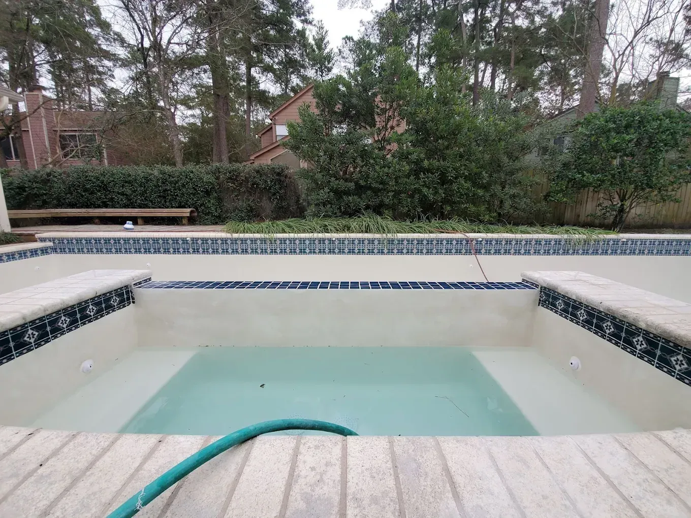 A hose is laying on the edge of a swimming pool