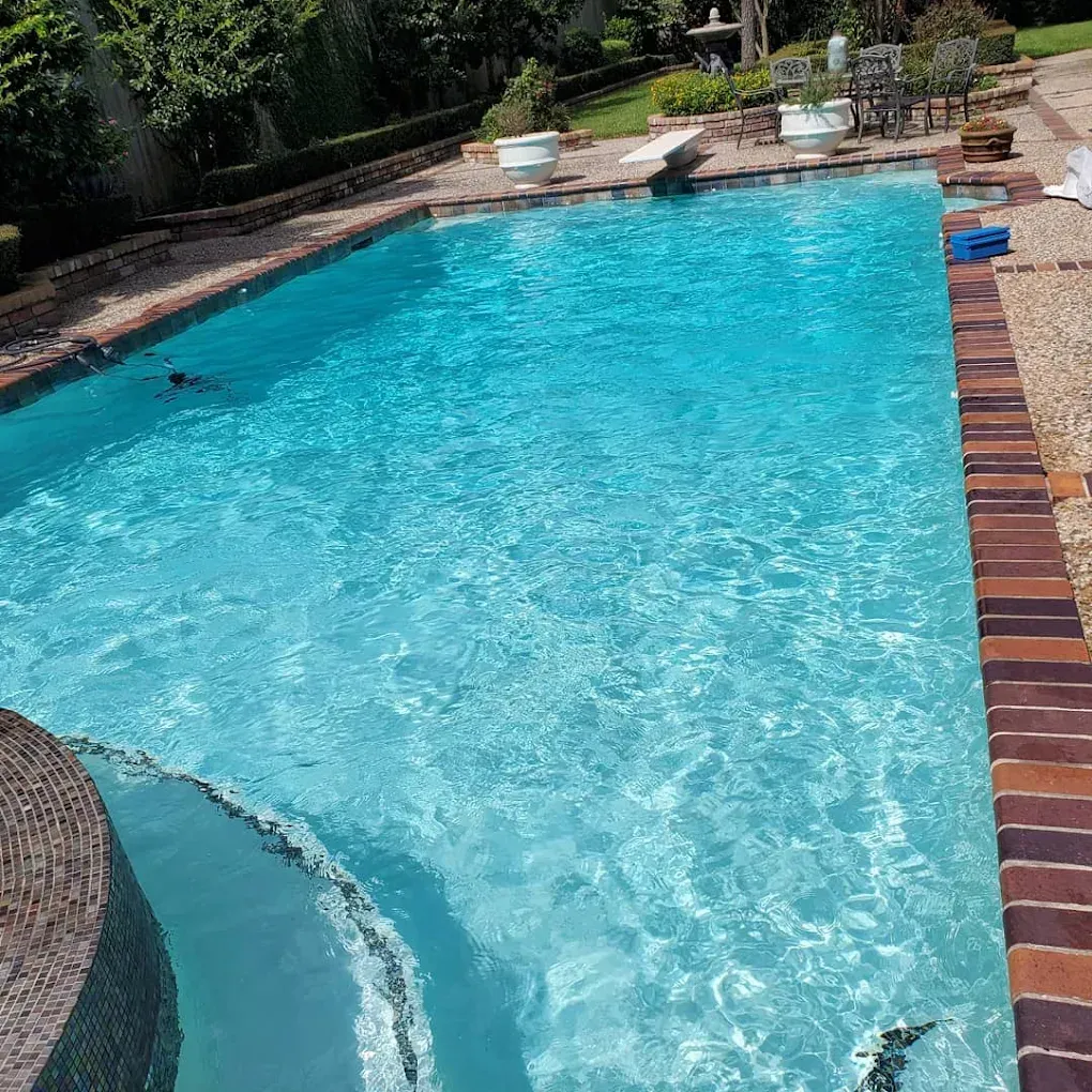 A large swimming pool filled with blue water and a brick border.