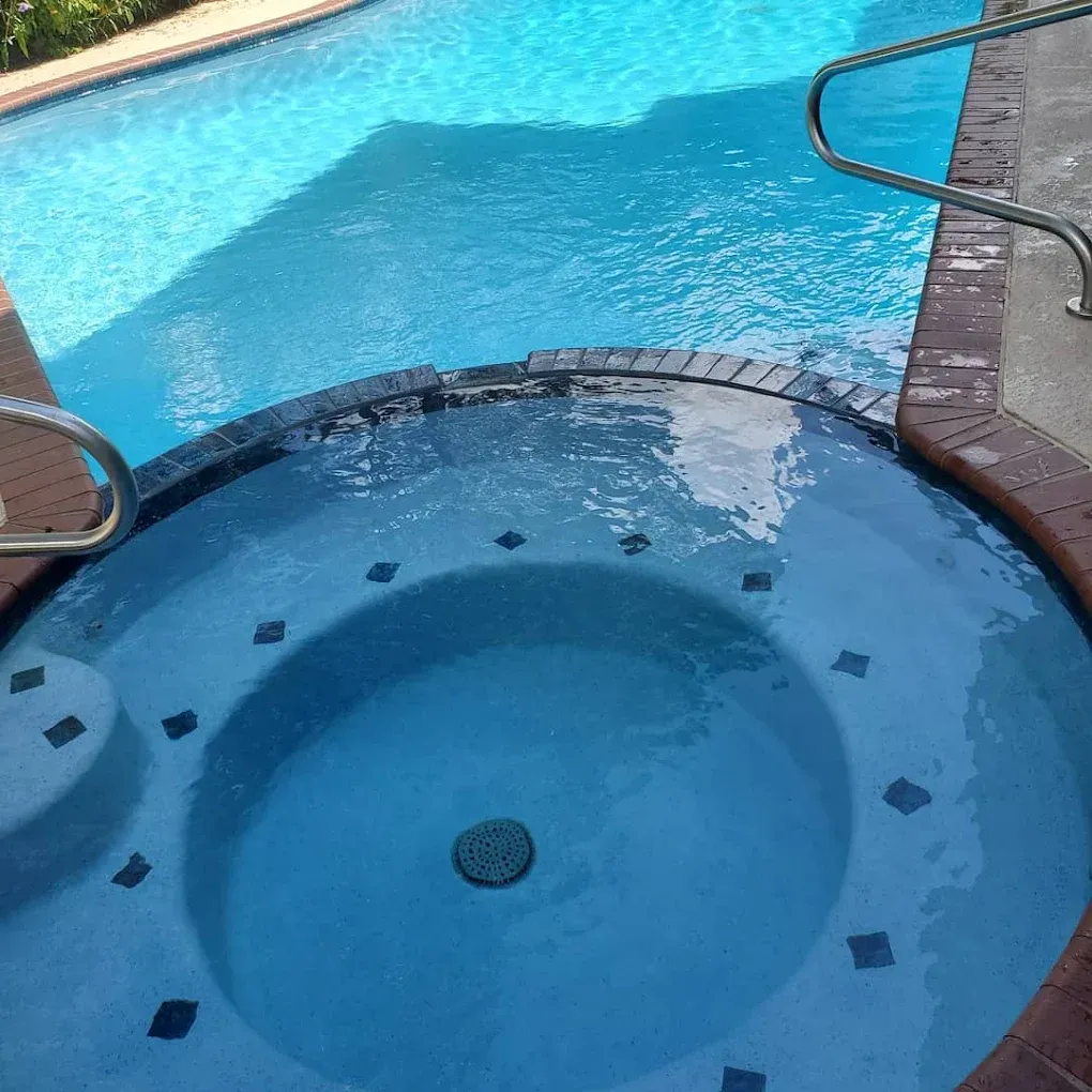 A jacuzzi next to a large swimming pool