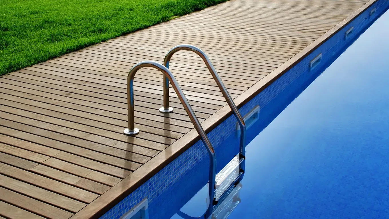 A swimming pool with a wooden deck and stairs