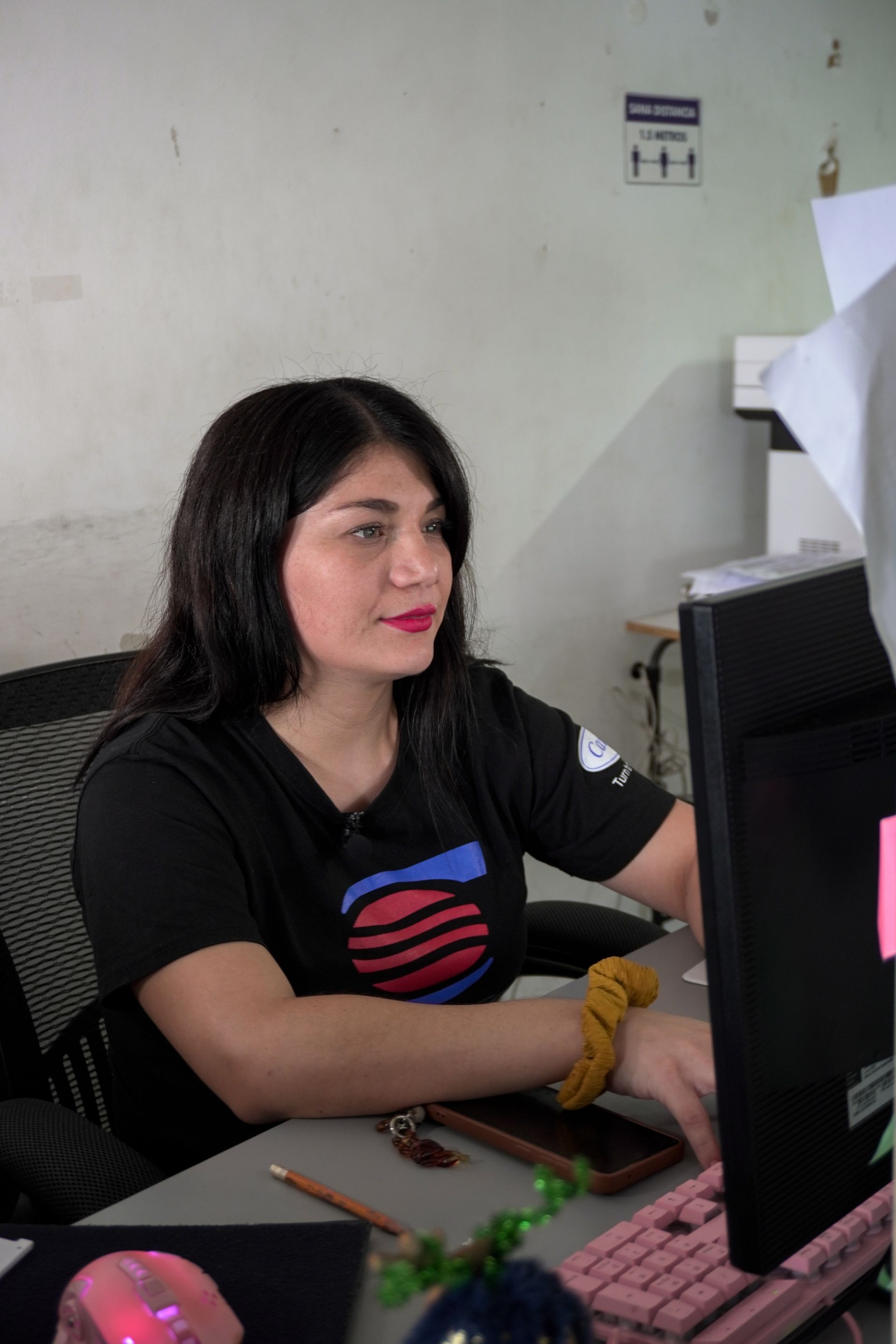 Una mujer está sentada en un escritorio frente a una computadora.