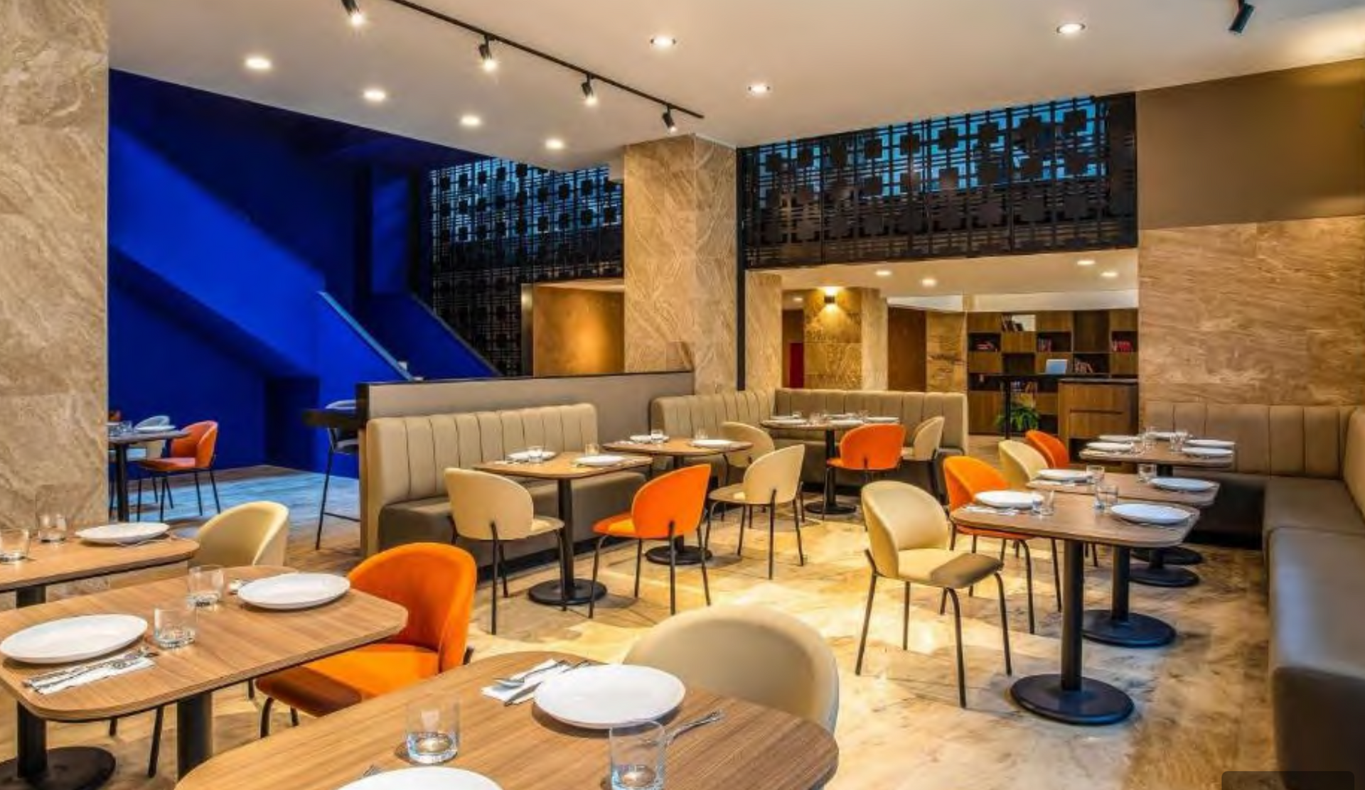 Un restaurante con mesas, sillas y platos encima.