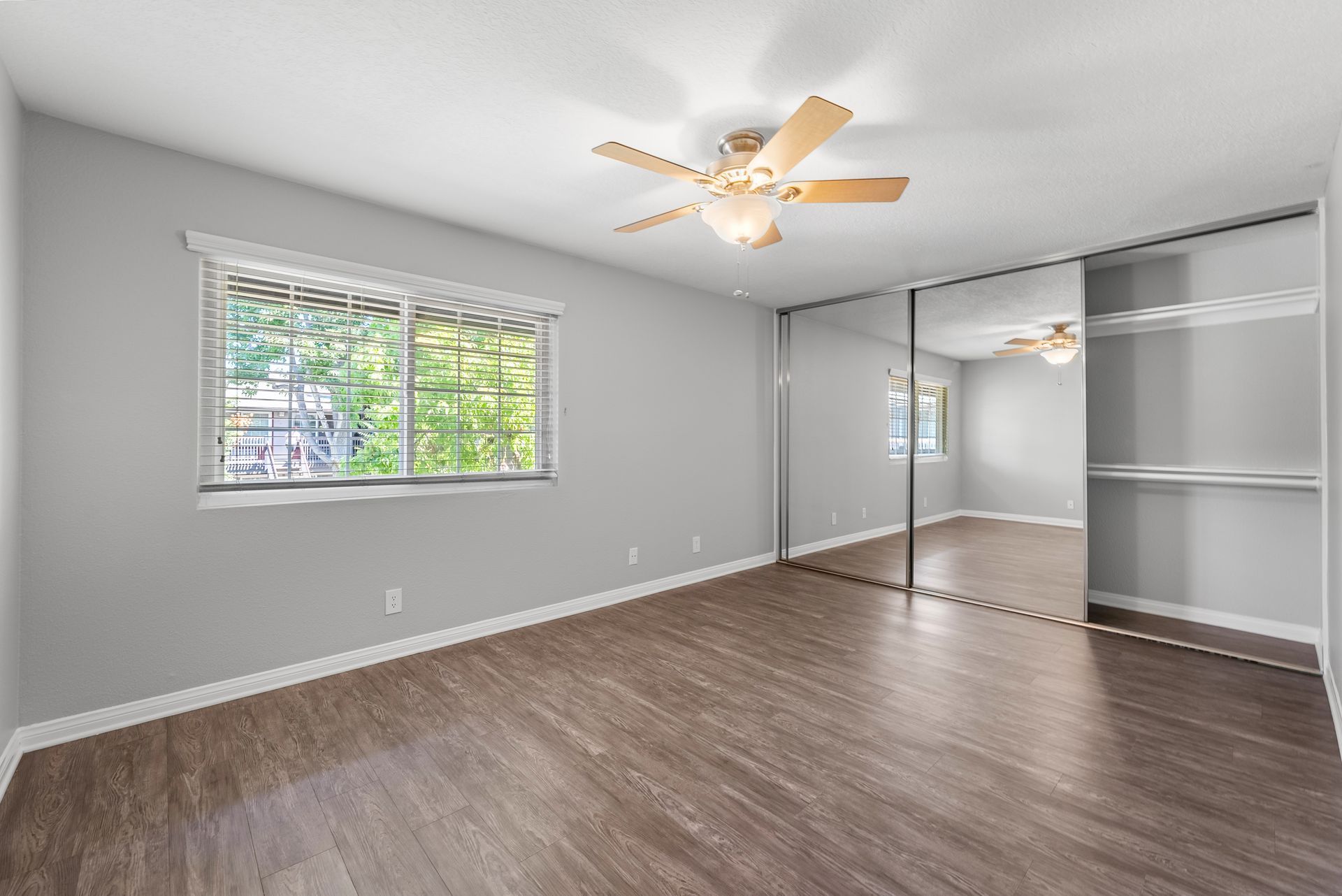 bedroom with ceiling fan and mirrored door