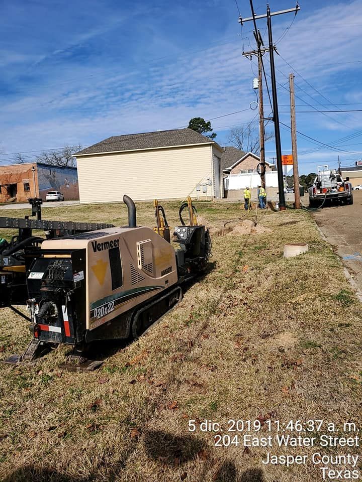 A directional boring machine on grass near utility poles and a street in Jasper County, Texas.