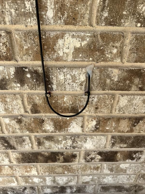 Black wire looped on brick wall, held by clip.