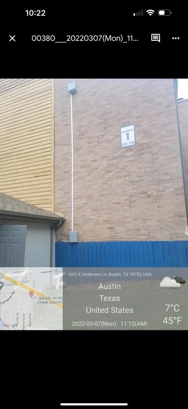 Exterior of a building with a blue barrier and a weather app displaying the temperature in Austin, Texas.