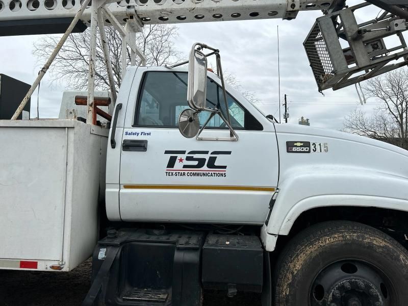 White TSC utility truck with logo, crane, and work basket.