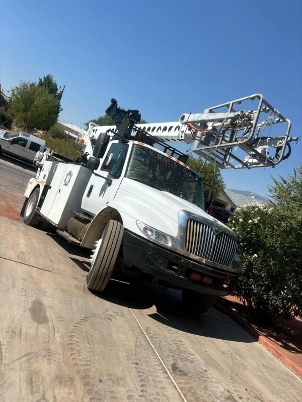 White utility truck with an extended boom on a residential street.