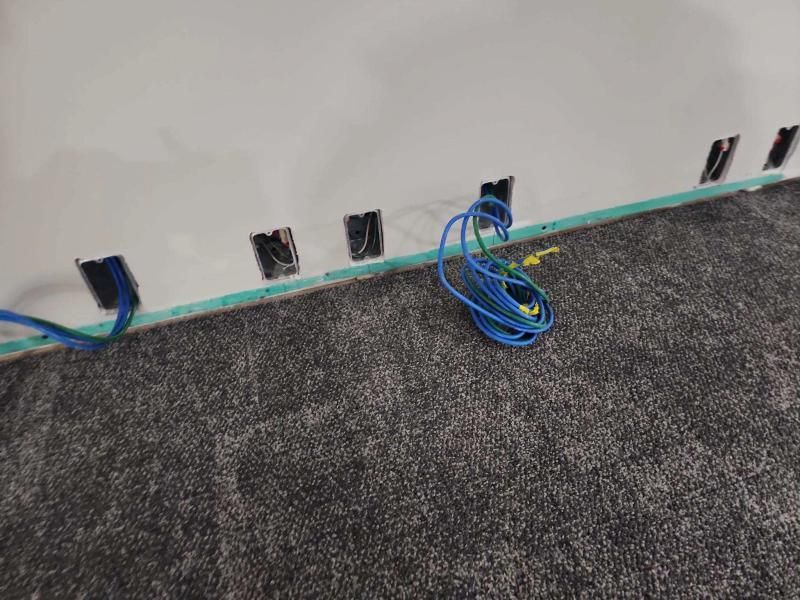 Blue Ethernet cables near wall with several open, empty boxes in it, carpeted floor.