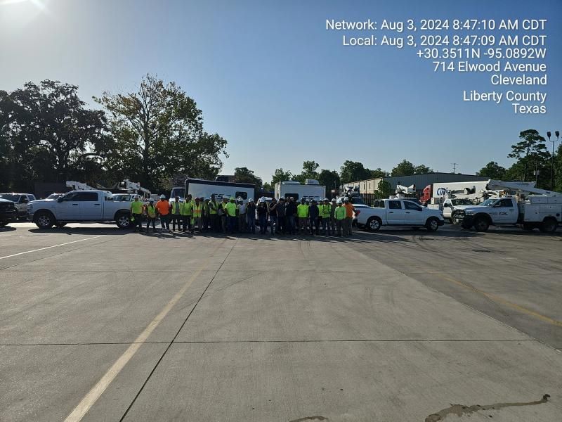 Group of people in safety vests and vehicles in a parking lot, Cleveland, Texas.