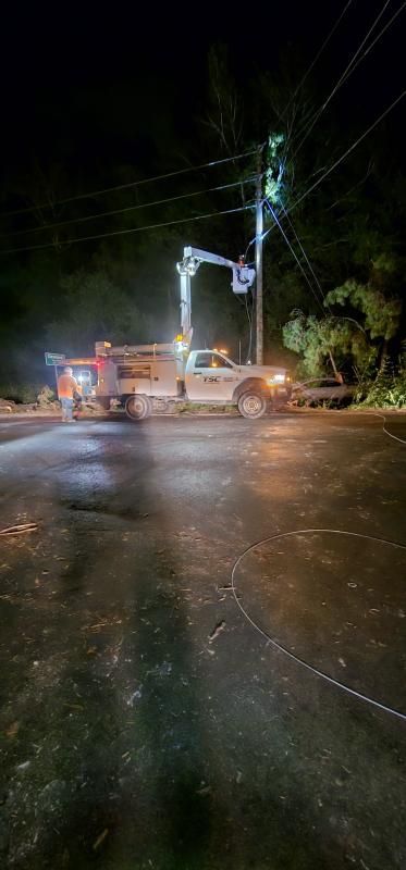 Utility truck and workers repairing power lines at night.
