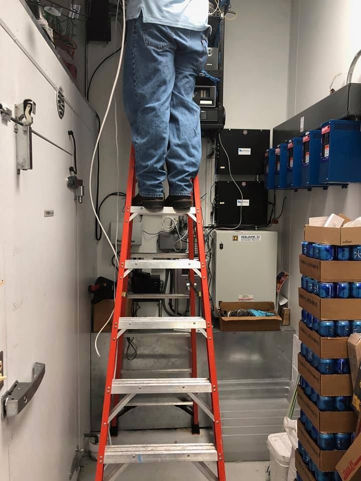Person on a red ladder working on equipment in a room.