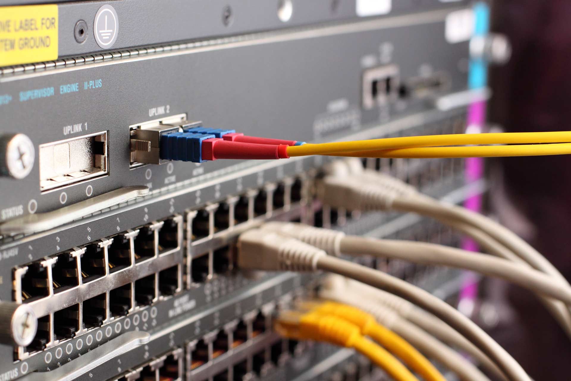 Network server with various cables plugged into ports, including fiber optic and Ethernet cables.