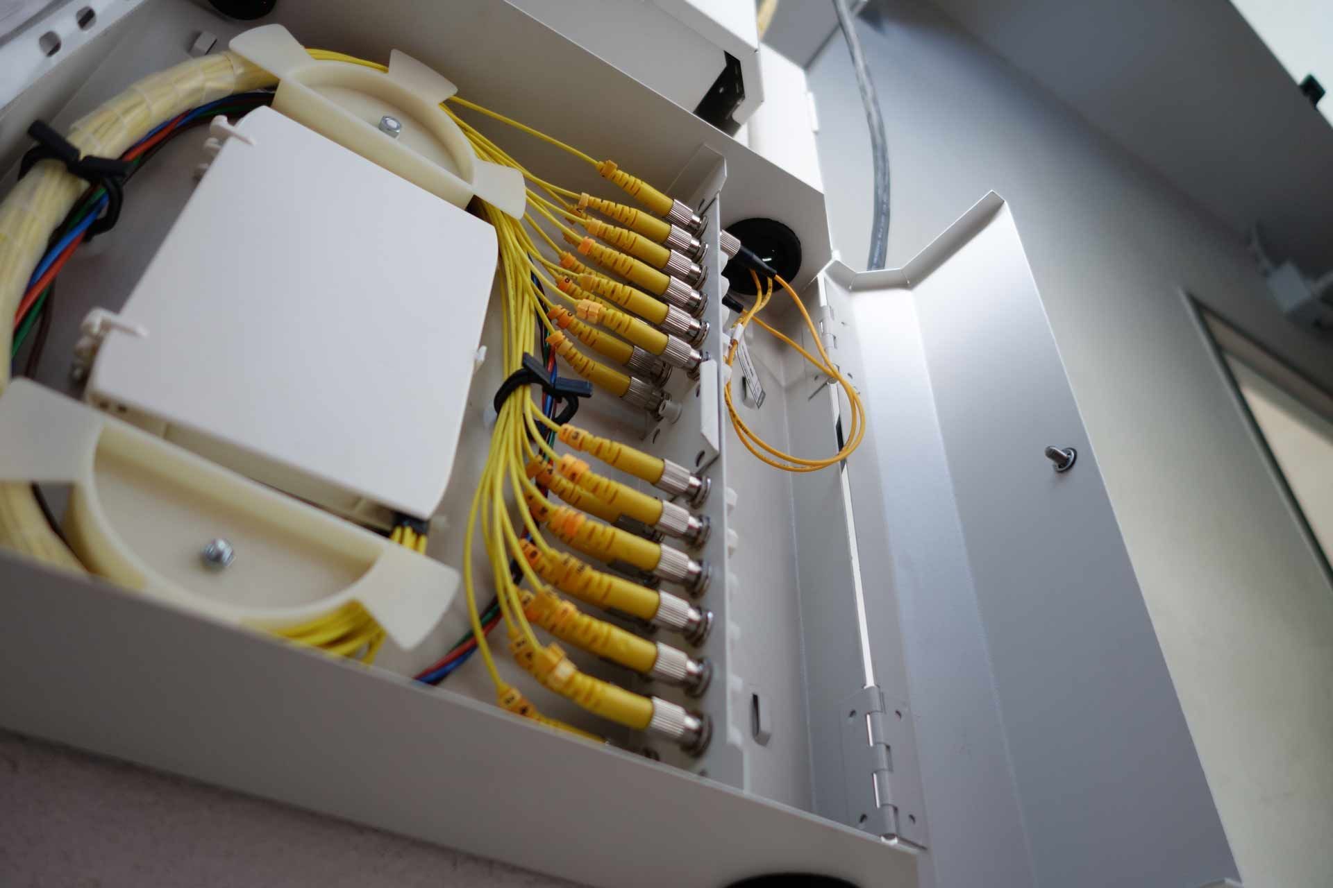 Open fiber optic terminal box with yellow fiber optic cables and white components.