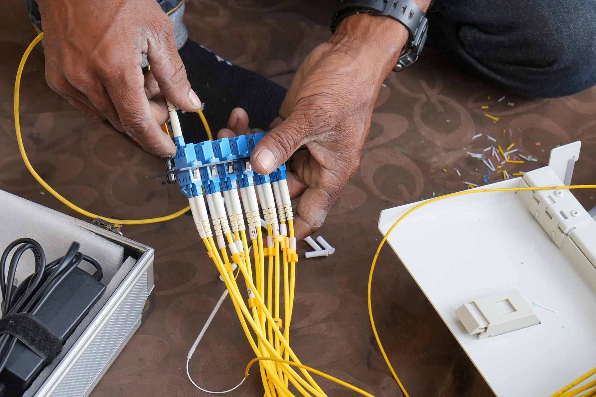 Person working with fiber optic cables and connectors.
