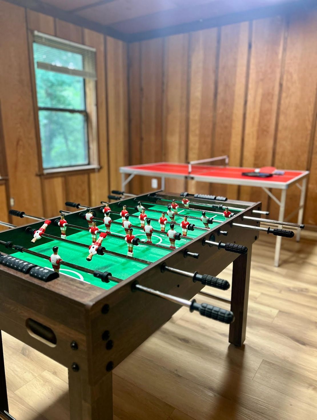 A game room with a foosball table and ping pong table