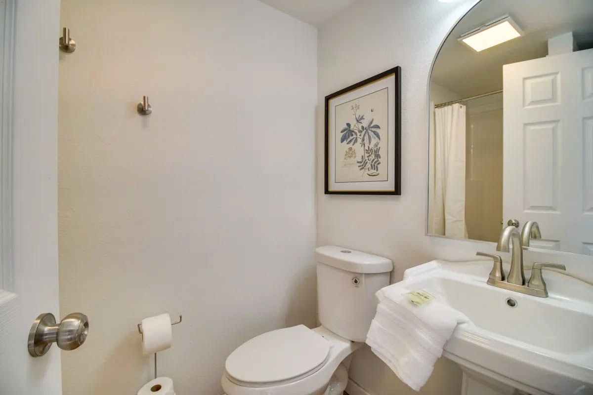A bathroom with a toilet , sink and mirror.
