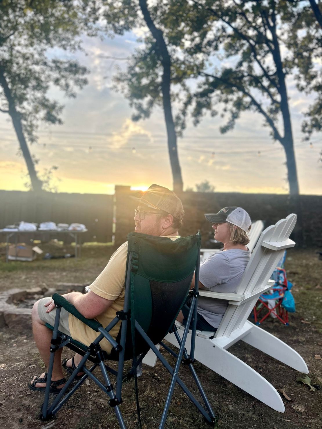 A man and a woman are sitting in lawn chairs watching the sunset.