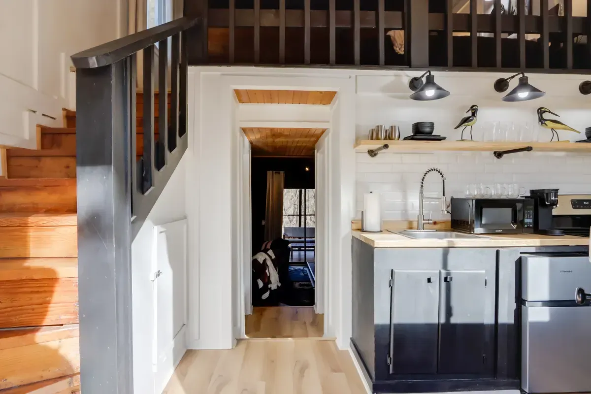 A kitchen with a sink , stove , microwave and stairs leading to the second floor.