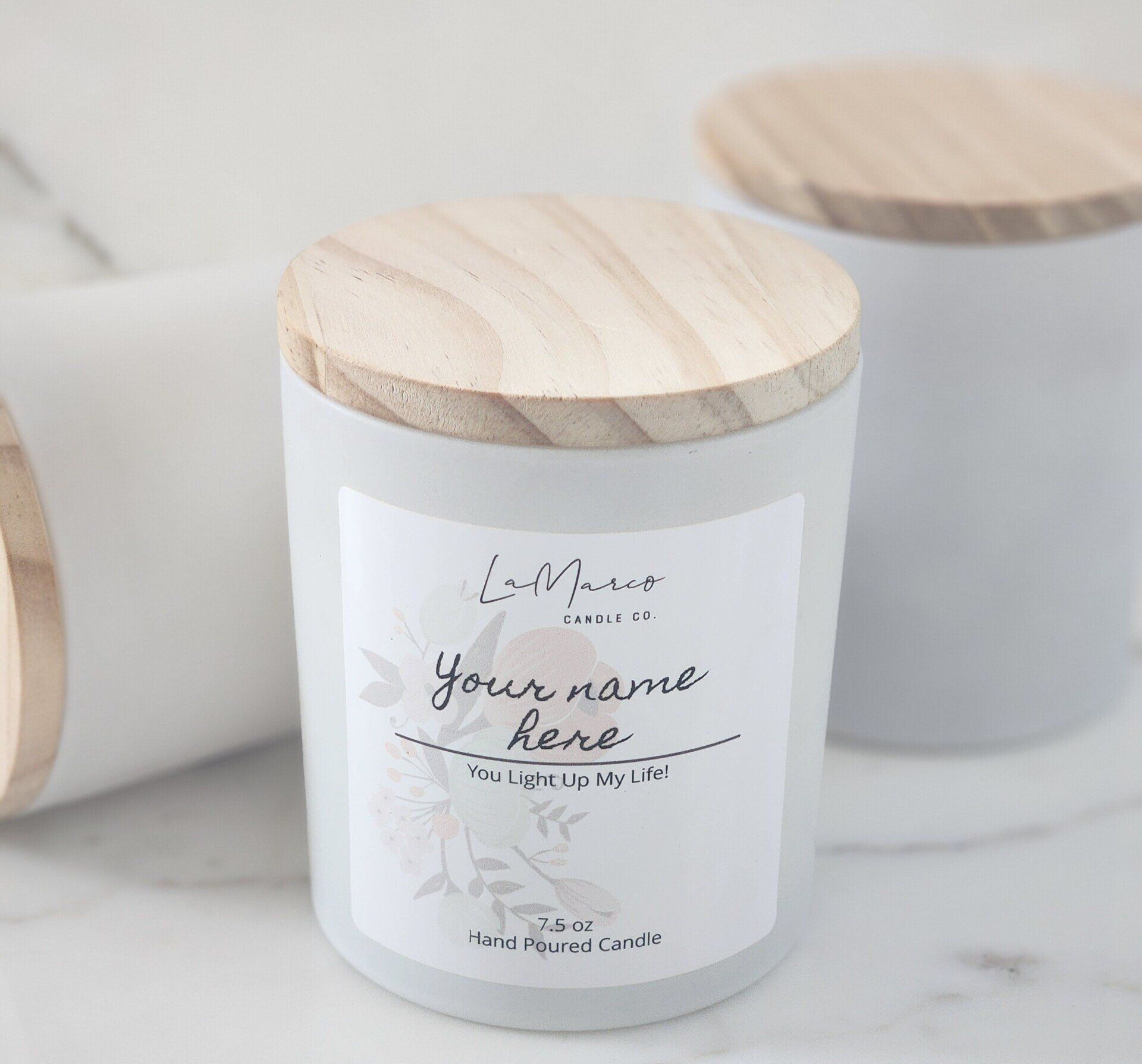 White candle with wooden lid and a label that says, 