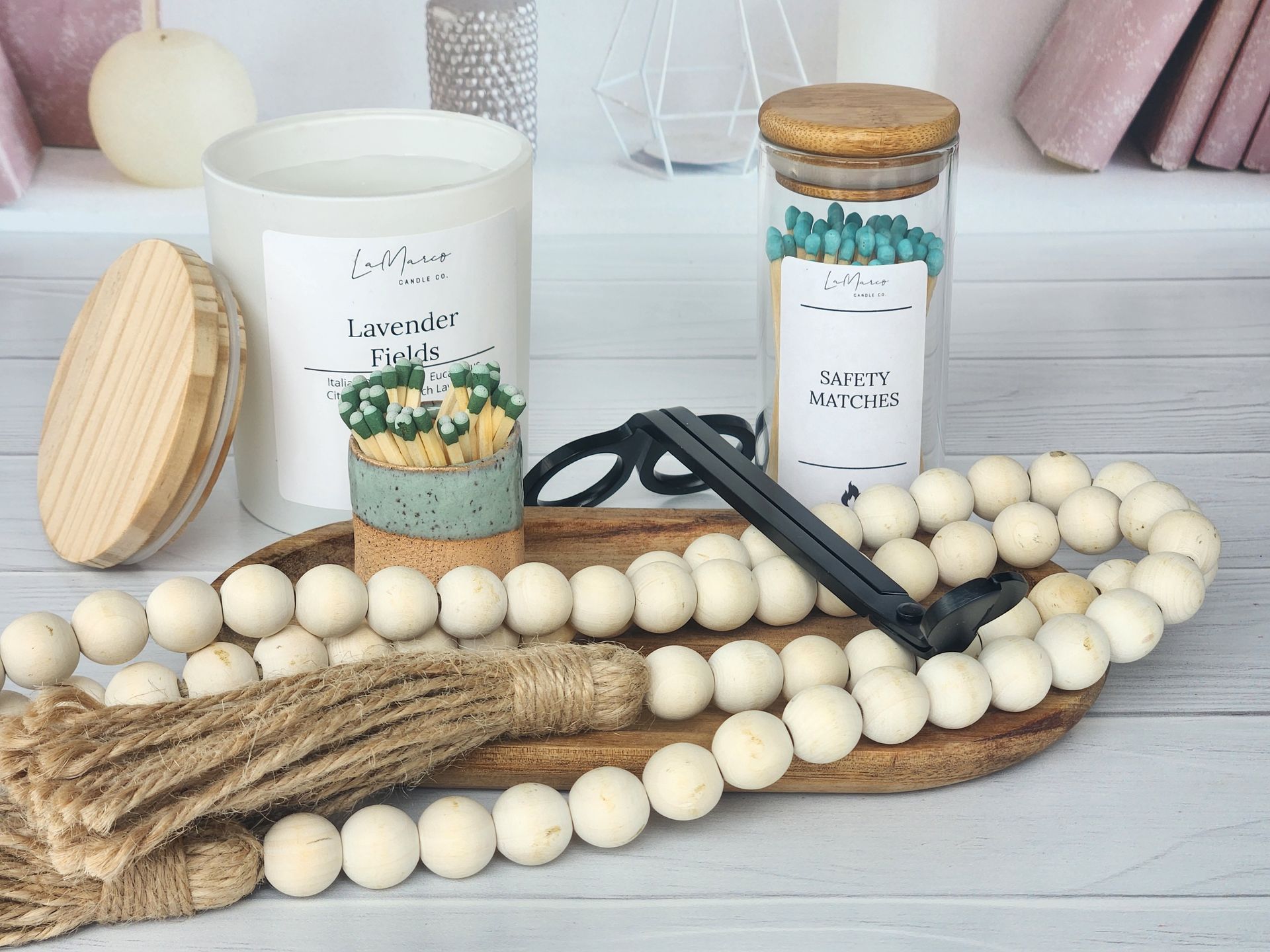Wooden tray with candle, match jar, beads, tassel, and matches.