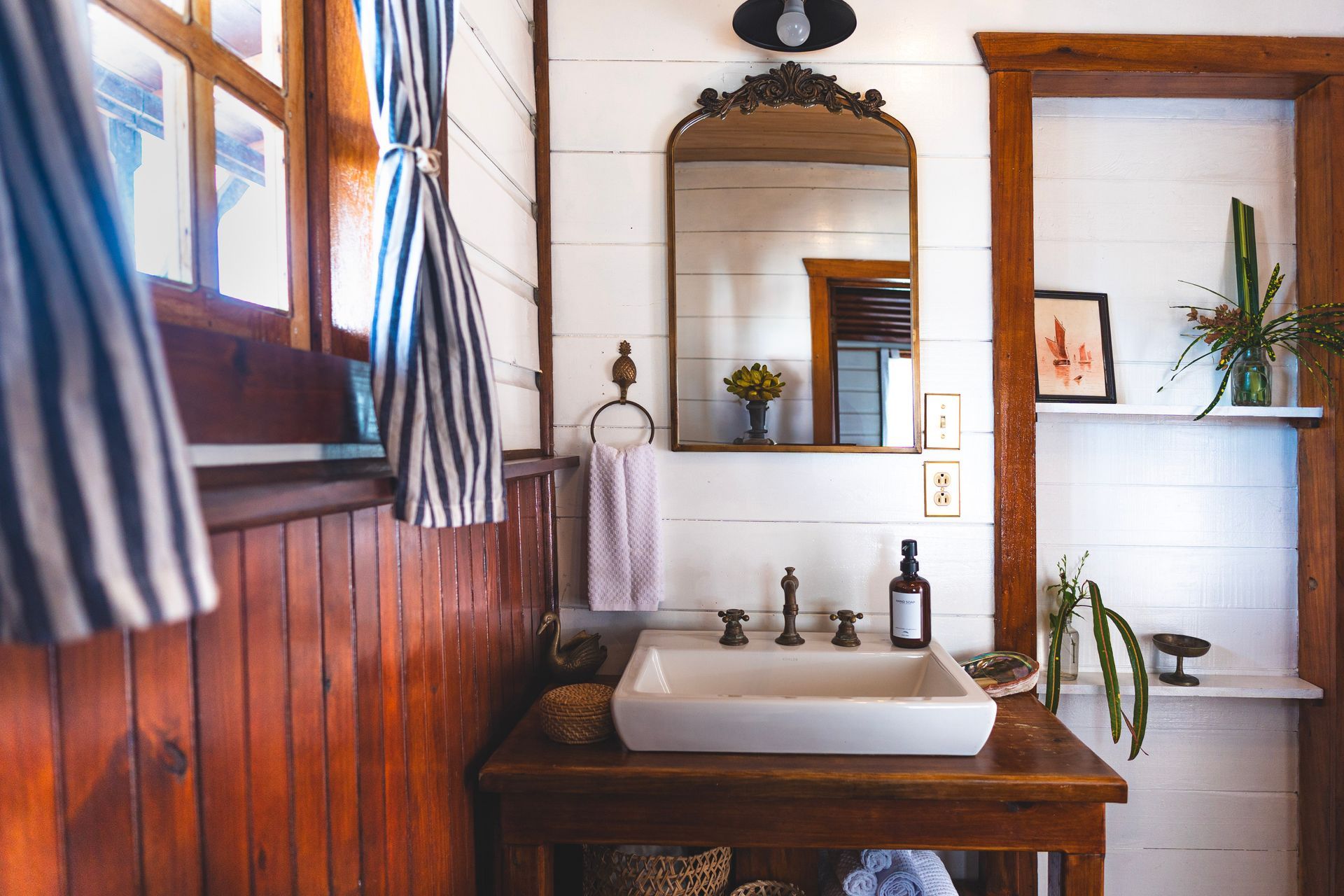 A bathroom with a sink , mirror and wooden walls.