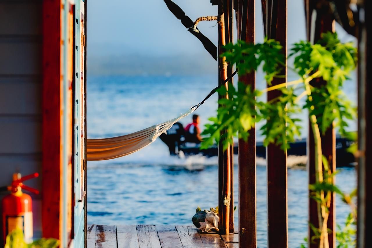 A hammock is hanging on a porch overlooking the ocean.