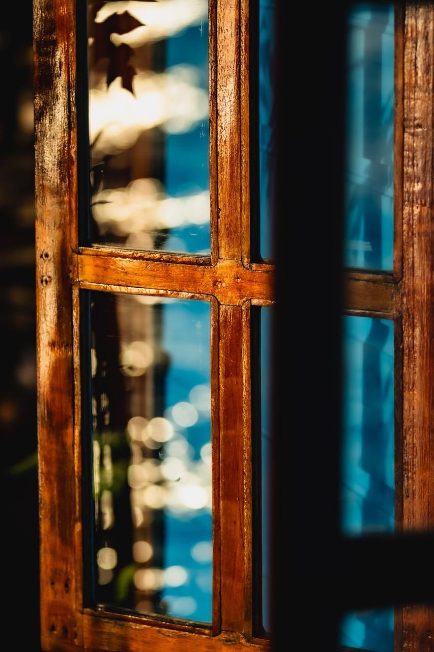 A close up of a wooden window with a reflection of a tree in the window.