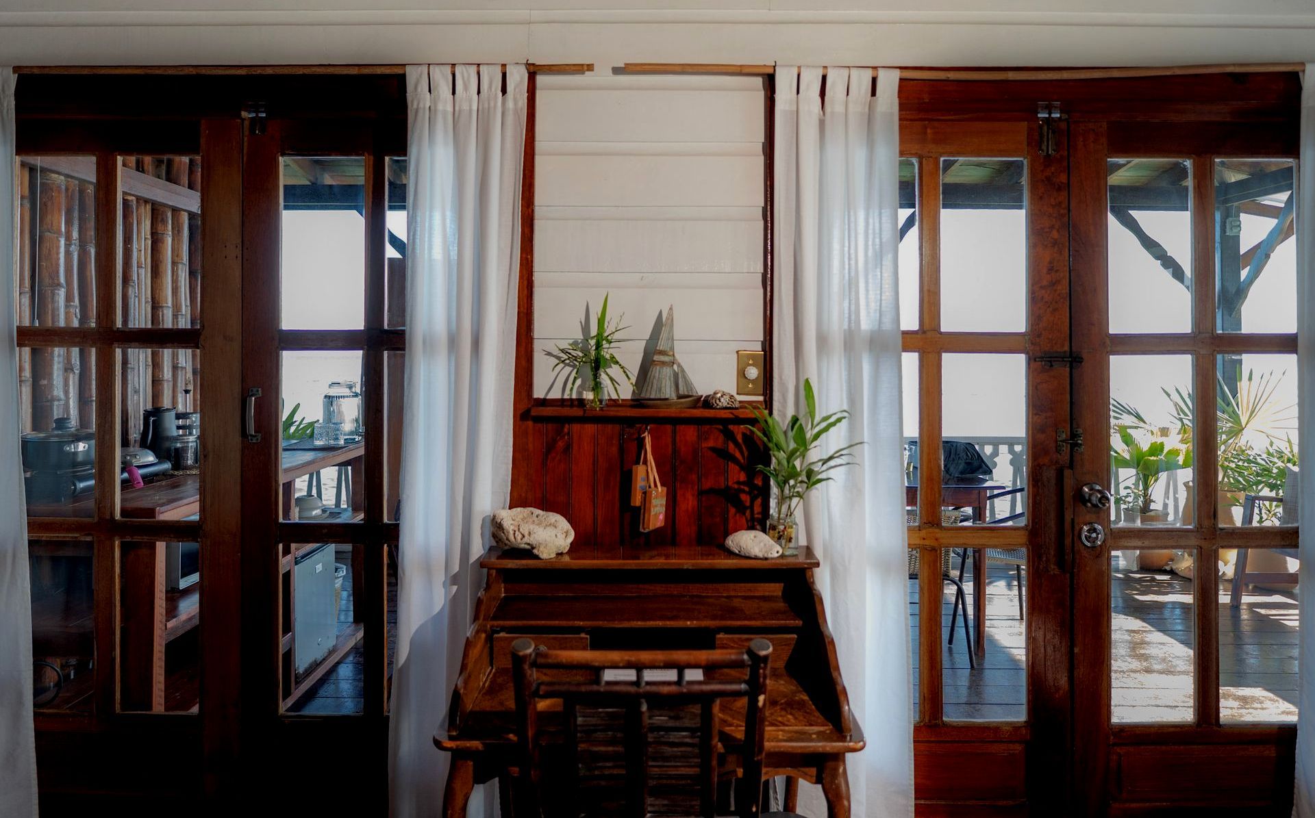 A wooden desk with a chair in a room with a lot of windows.