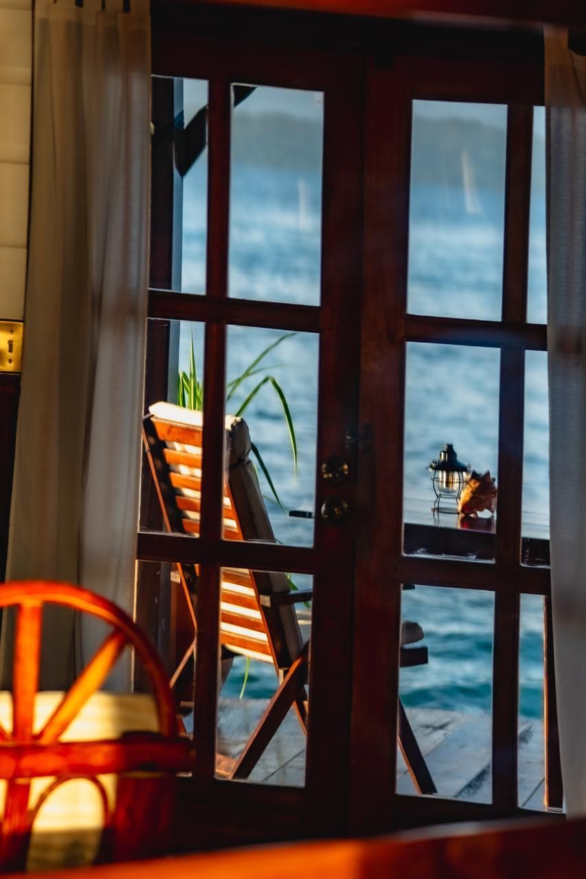A view of the ocean through a window with a chair in the background