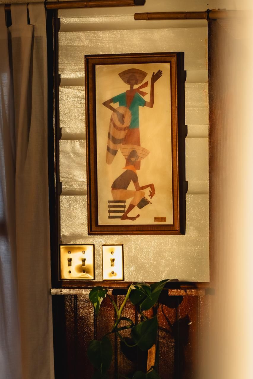 A painting is hanging on a wall next to a plant.