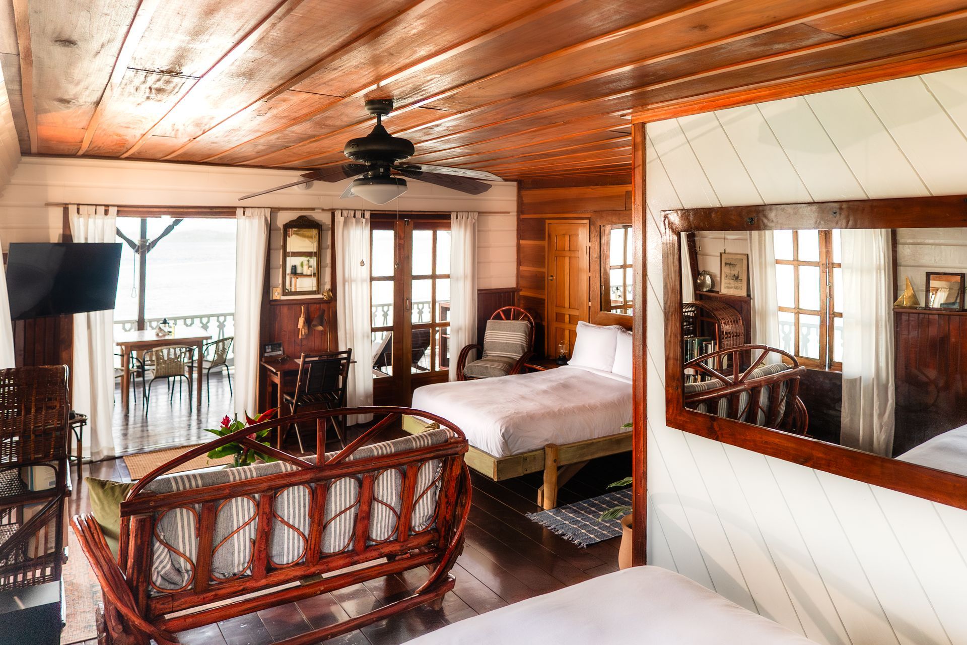 A hotel room with two beds , a couch , a mirror and a ceiling fan.