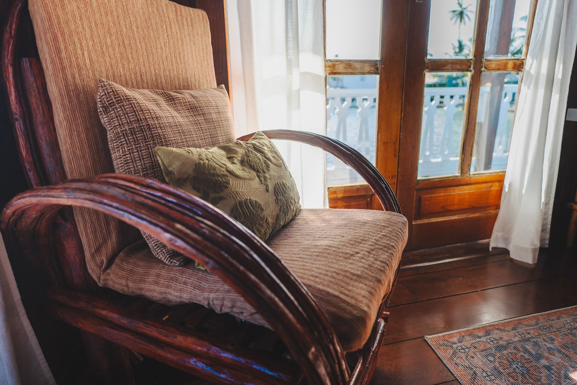 A wicker chair with a pillow on it is sitting in front of a window.