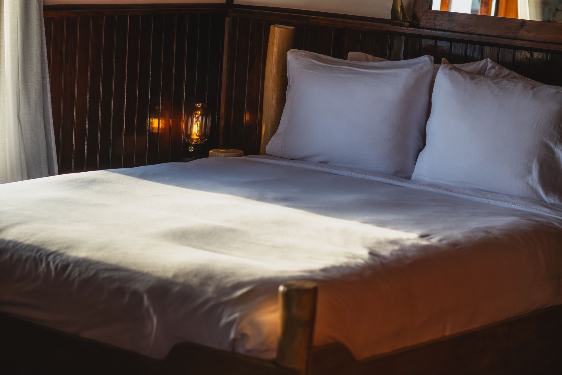 A bed with white sheets and pillows in a hotel room.