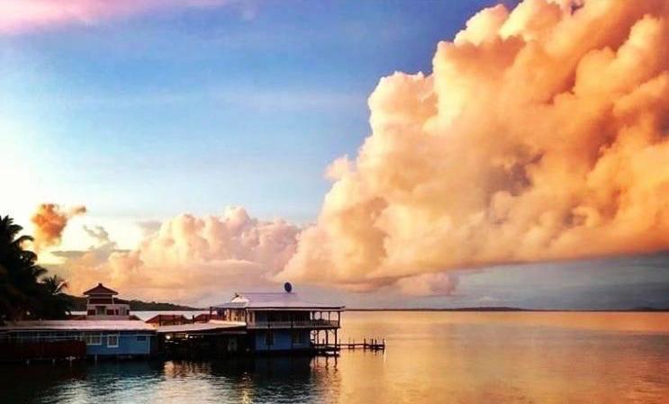 A sunset over a body of water with a house in the foreground