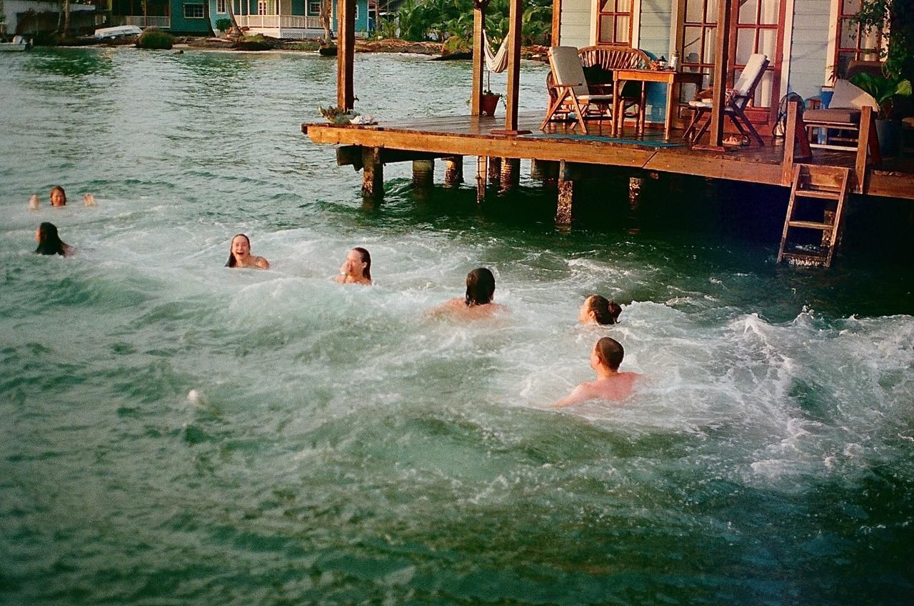 A group of people are swimming in the water near a dock.