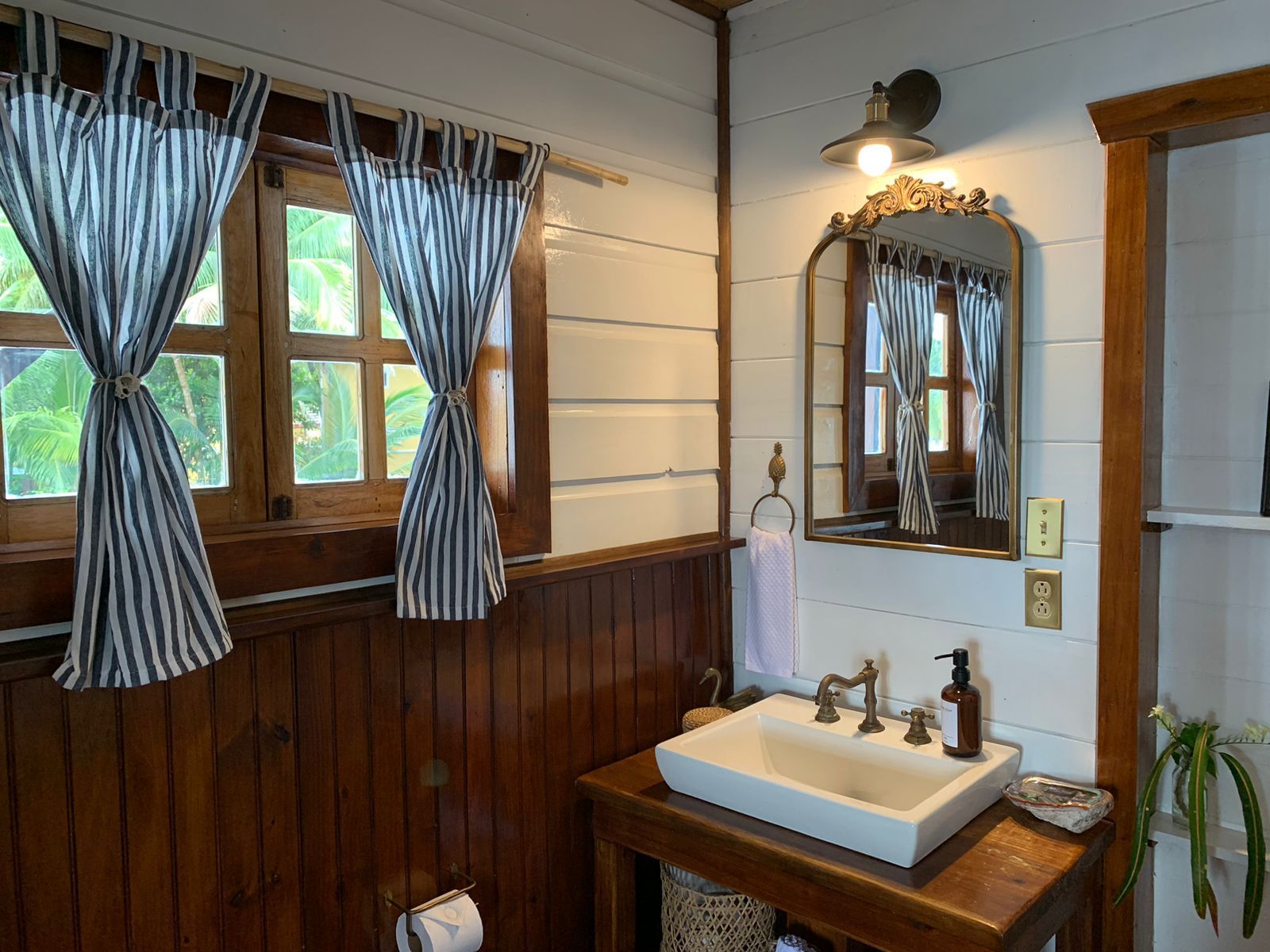 A bathroom with a sink , mirror and window.