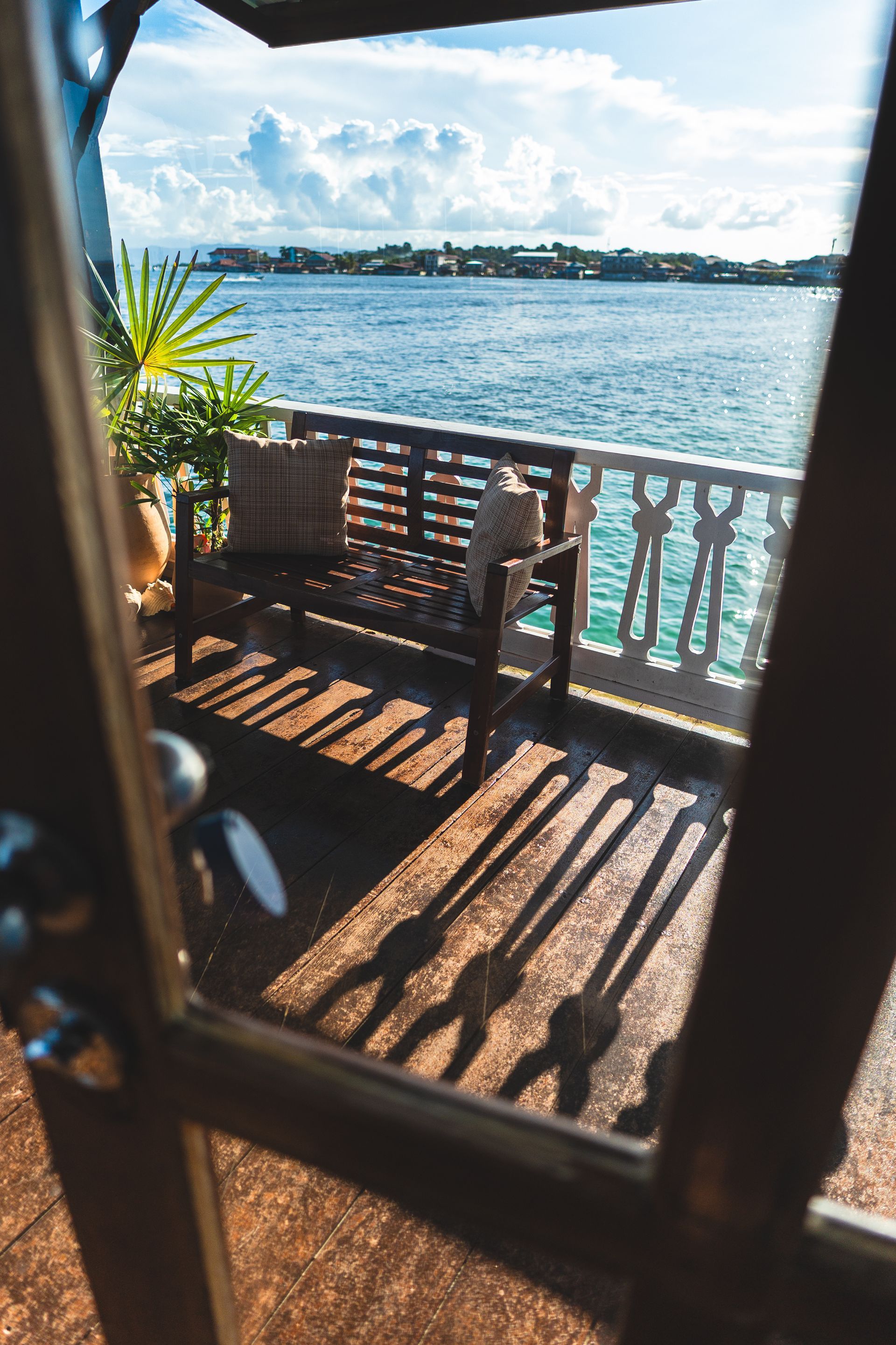 A wooden bench is sitting on a balcony overlooking the ocean.