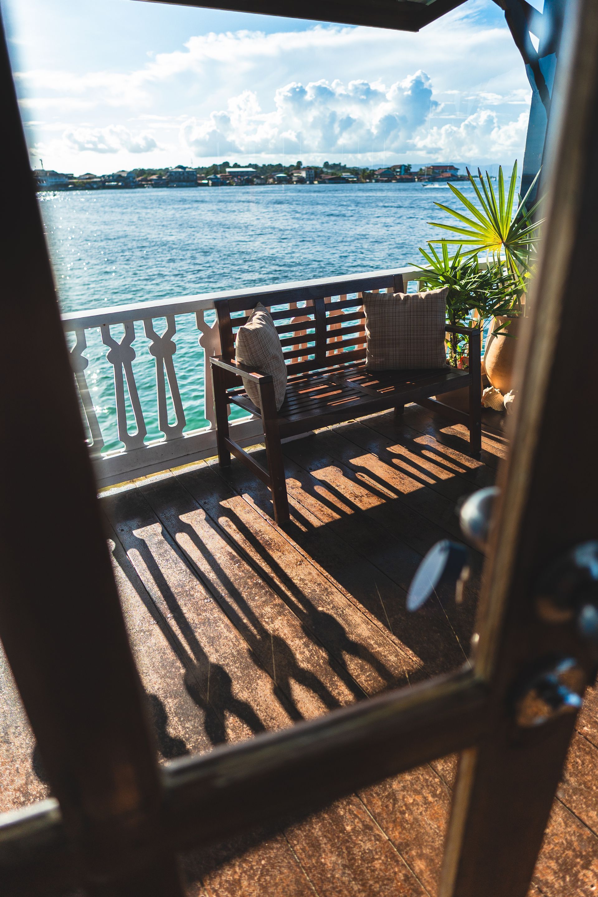 A wooden bench is sitting on a balcony overlooking the ocean.