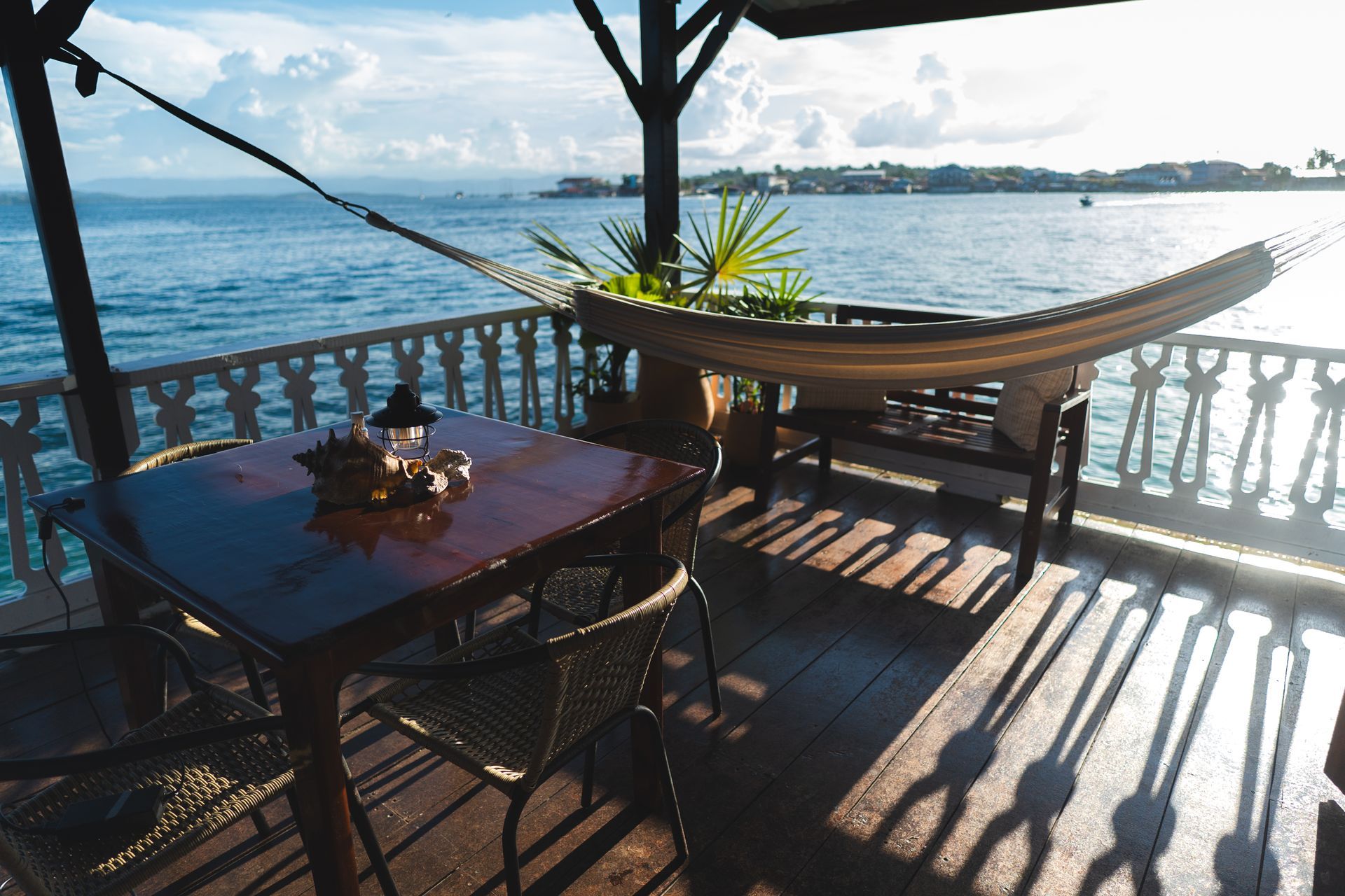 There is a table, chairs, and hammock on the deck overlooking the ocean.