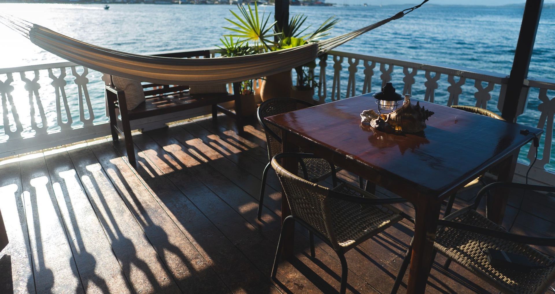 A table and chairs on a deck overlooking the ocean.