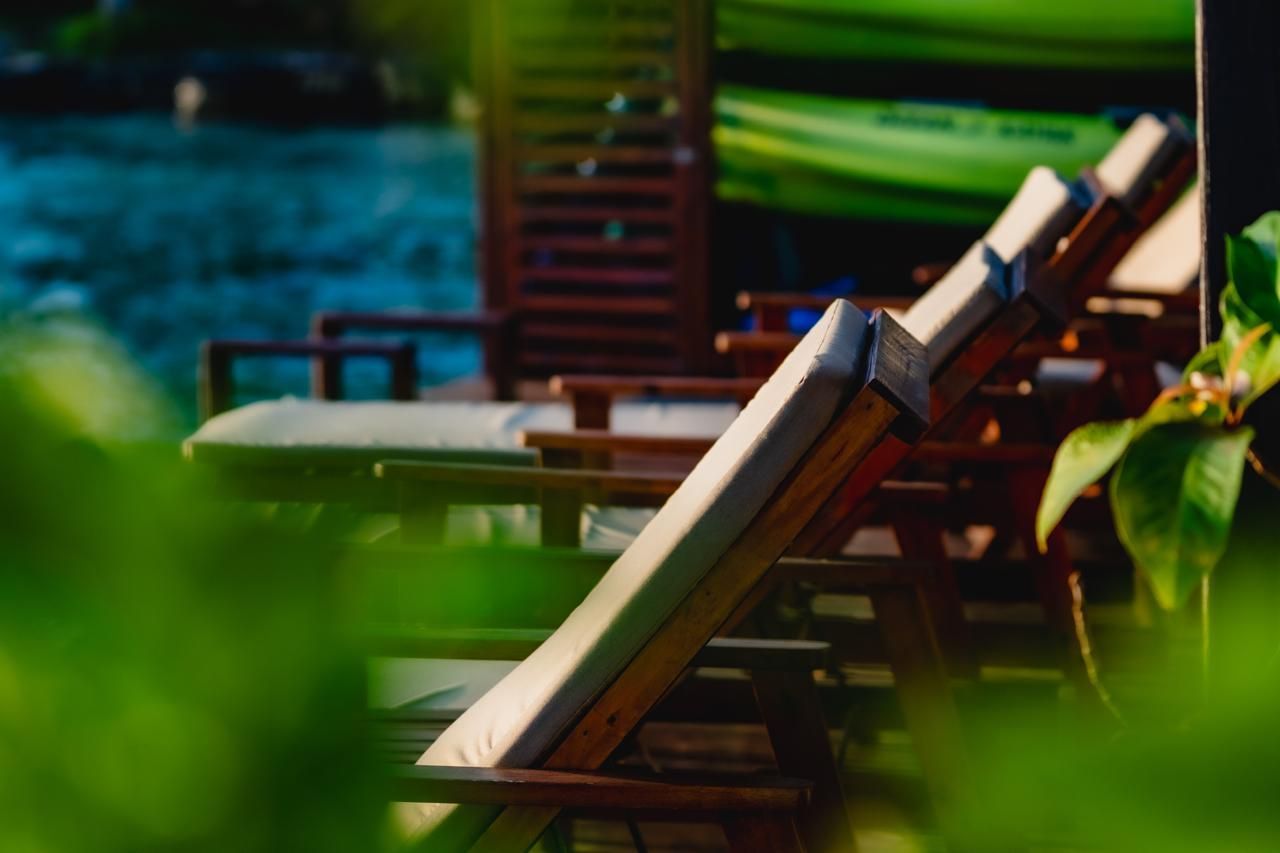 A row of lawn chairs are sitting next to a swimming pool.