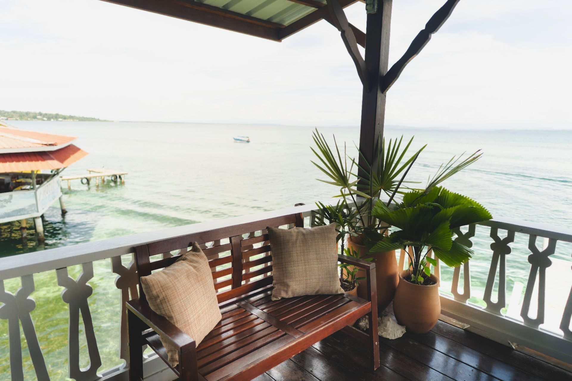 A wooden bench on a balcony overlooking the ocean.
