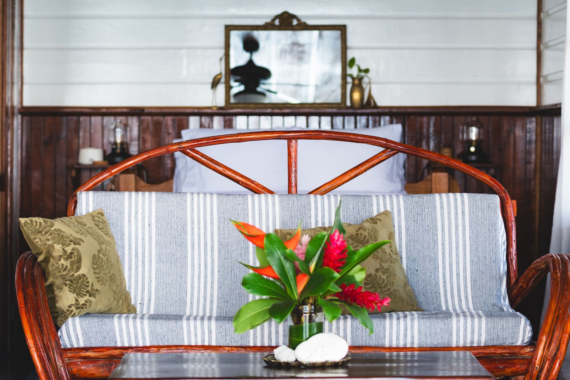 A living room with a couch and a table with a vase of flowers on it.
