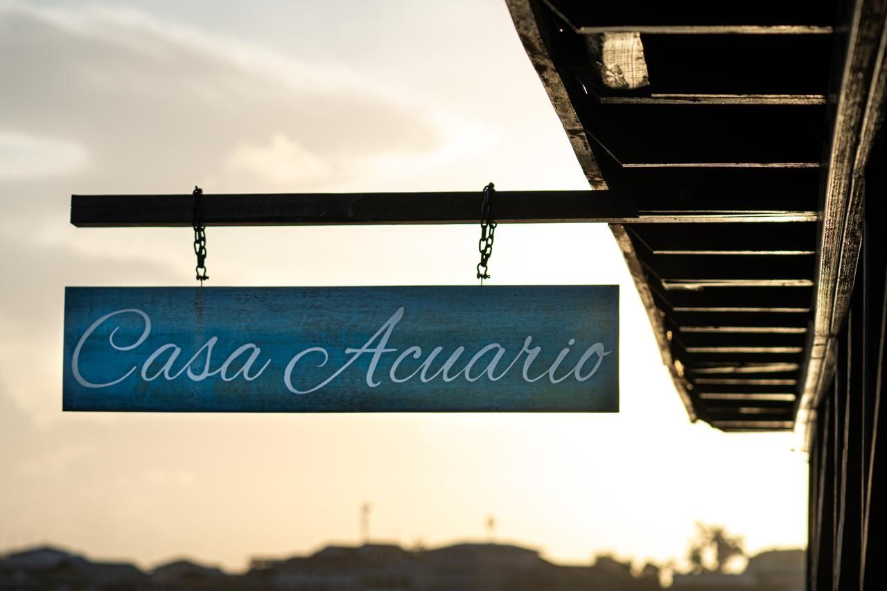 A blue sign that says casa acuario hangs from the side of a building
