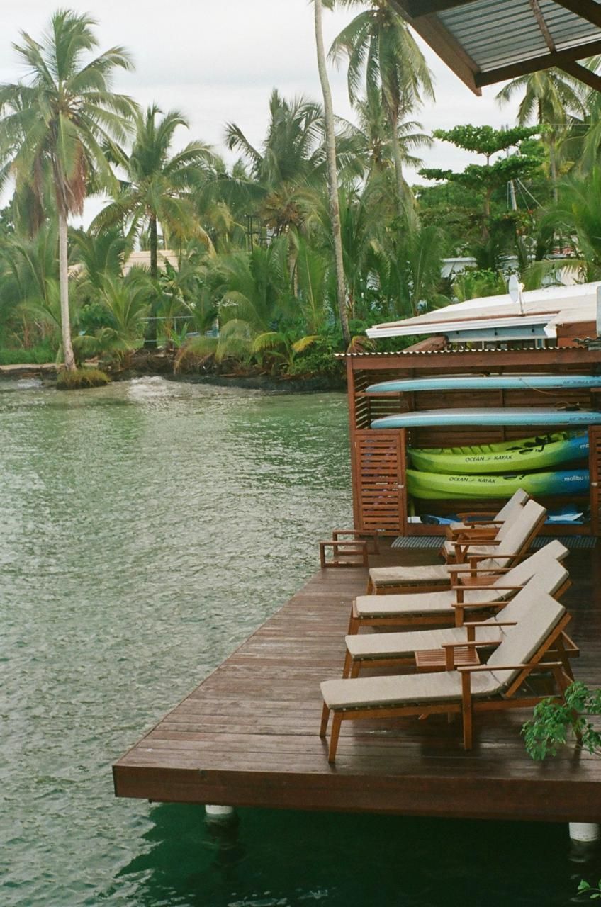 A dock with chairs and surfboards on it overlooking a body of water