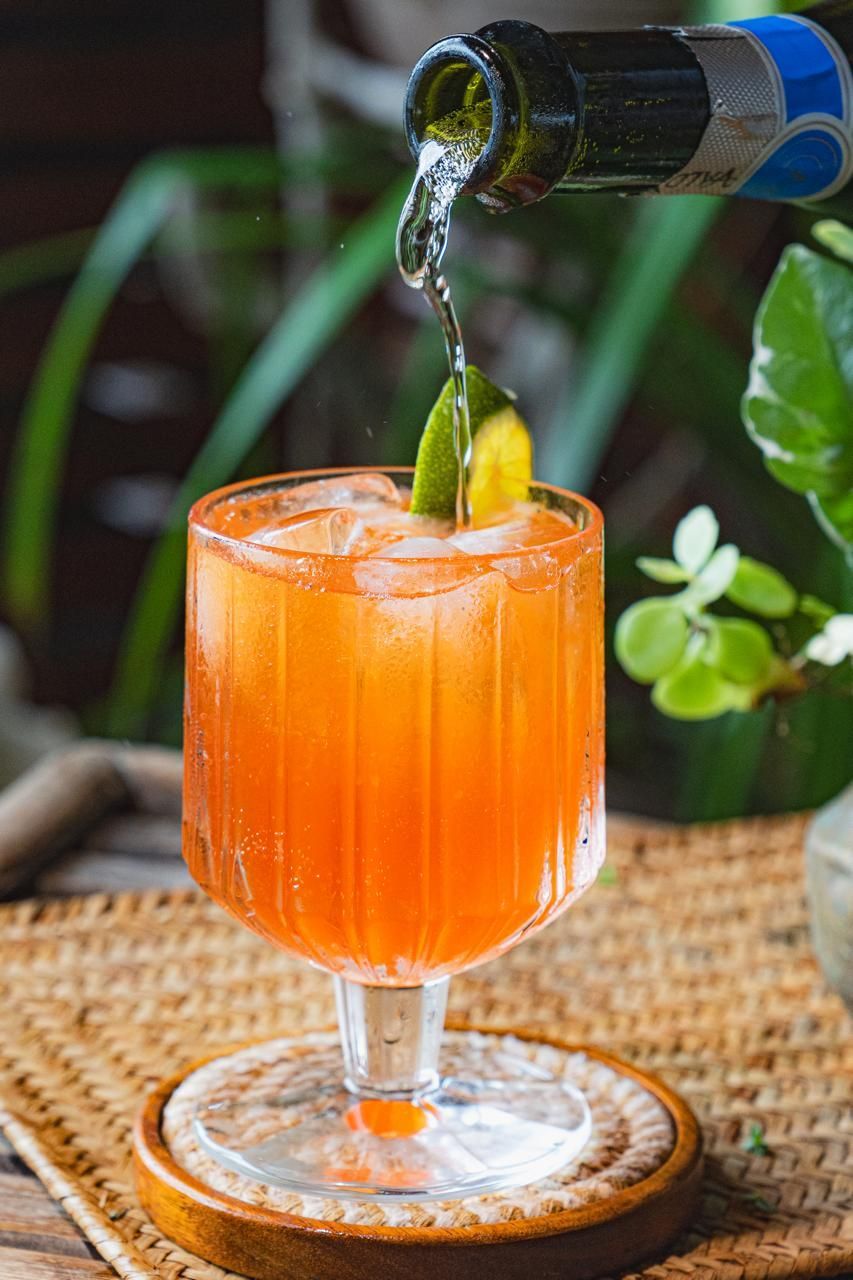 A close up of a drink being poured into a glass on a table.