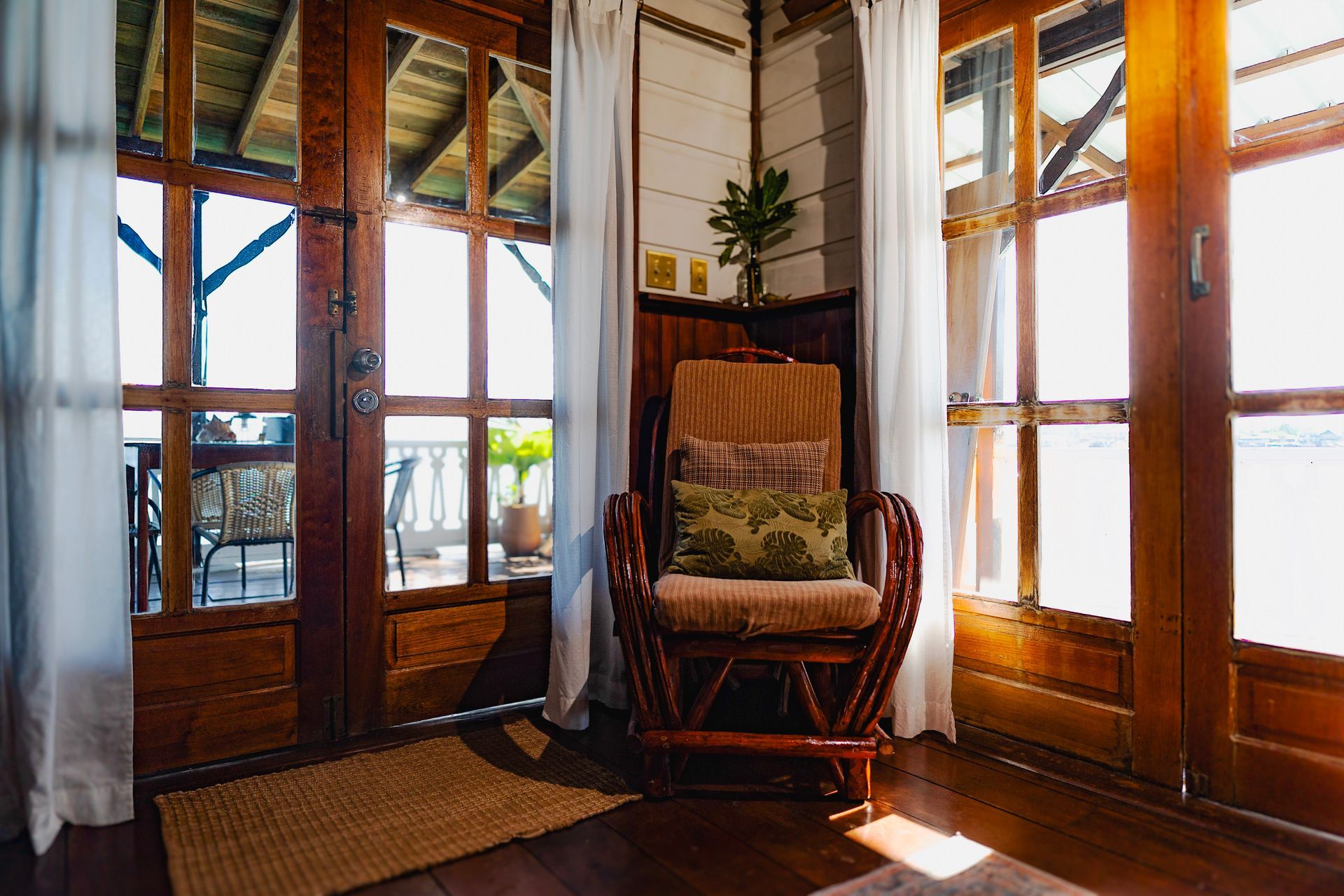 A wooden rocking chair is sitting in a room next to a window.