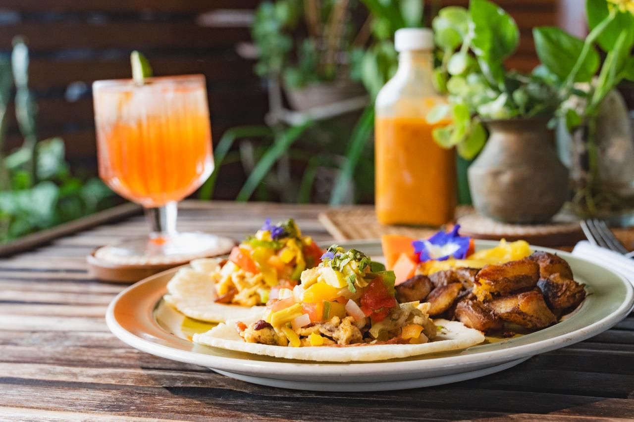 A plate of food and a glass of orange juice on a wooden table.