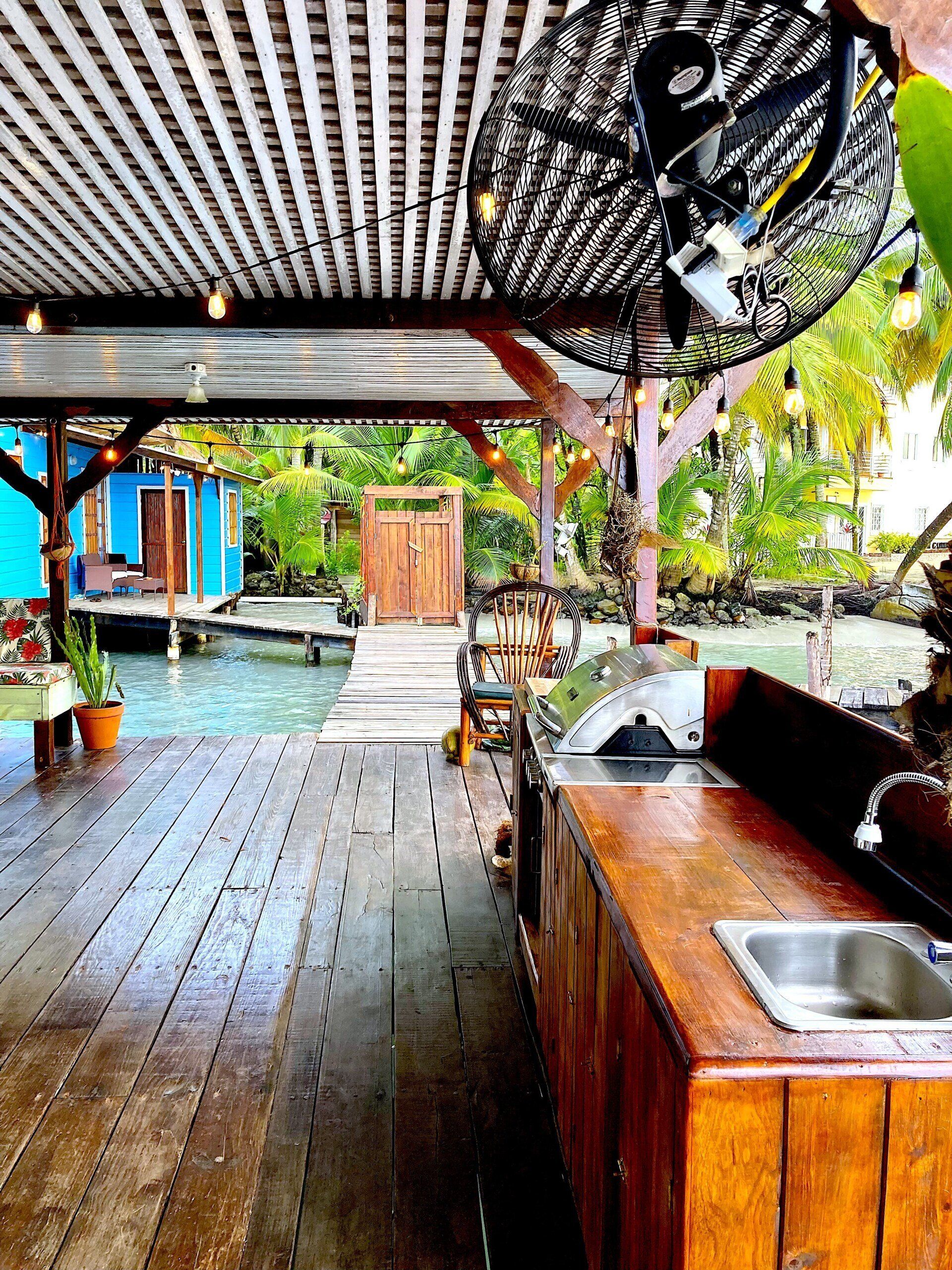 A wooden deck with a sink and a grill under a canopy.